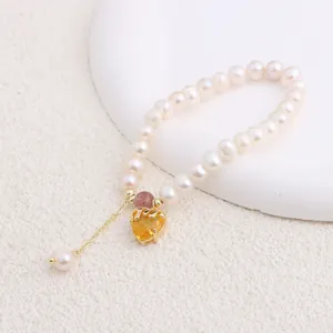 Close-up of a natural freshwater pearl bracelet featuring a vibrant yellow heart-shaped pendant
