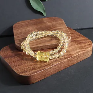 Close-up of yellow citrine beaded bracelet with a cute carved bear charm on wood