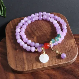 Primer plano de pulsera de dos hilos de piedra natural lavanda con colgante de jade blanco