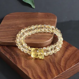 Detailed view of natural citrine bracelet with carved yellow crystal charm on wood