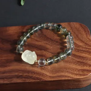 Macro detail of green phantom quartz bracelet featuring an intricate carved lion charm