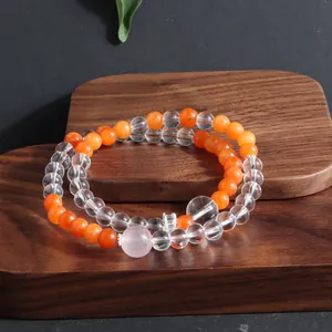 Detailed macro view of natural orange sunstone and clear crystal beaded bracelets on wood
