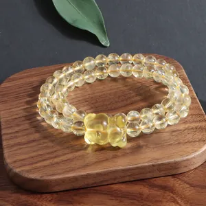 Macro detail of a natural citrine double-strand bracelet with a carved fox charm accessory