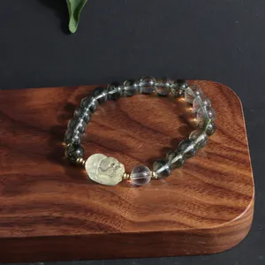 Macro view of green phantom quartz bracelet featuring a carved lemon yellow lion bead
