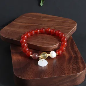 Nahaufnahme eines Armbands aus rotem Karneol mit einem Anhänger aus weißer Jade.