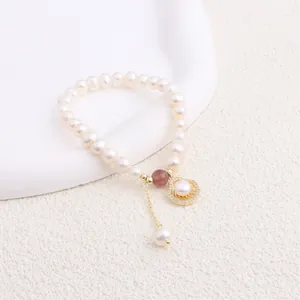 Close-up detail of a freshwater pearl bracelet with golden shell and crystal charms