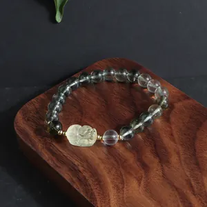 Close-up of green phantom quartz bracelet with carved yellow crystal lion charm