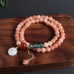 Primer plano de una pulsera de doble vuelta en piedra natural con detalle de colgante de jade