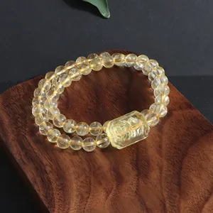 Close-up of double-strand natural citrine bracelet with carved fox plaque on wood.