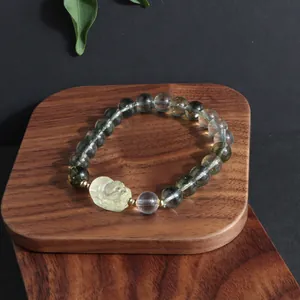 Close-up of green phantom and lemon quartz crystal bracelet with carved lion charm