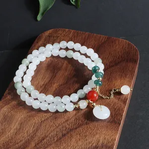 Vista detallada de una pulsera de piedra blanca de varias vueltas con dije de jade.