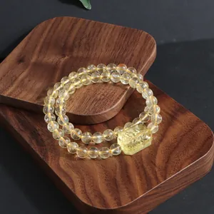 Macro view of natural citrine double-strand bracelet featuring a carved crystal pendant