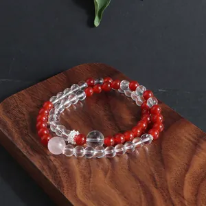 Close-up of double-layered natural crystal bracelet with red and clear beads on wood