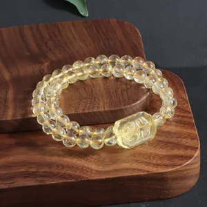 Close-up of yellow citrine beaded bracelet with a carved lemon quartz fox charm on wood.