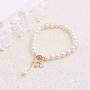 Elegant macro view of the gold bee pendant with zircon crystals on a pearl bracelet