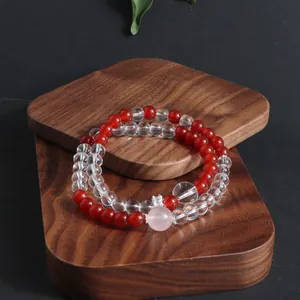 Detail of natural stone crystal bracelet with red and clear beads on wood