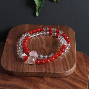 Detail view of red and clear natural stone crystal bracelet on a wooden tray