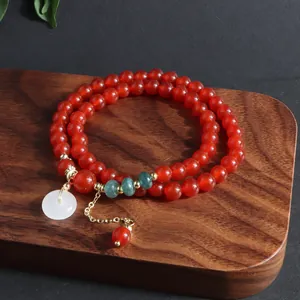 Primer plano de una pulsera de ágata roja de varias vueltas con colgante de jade blanco