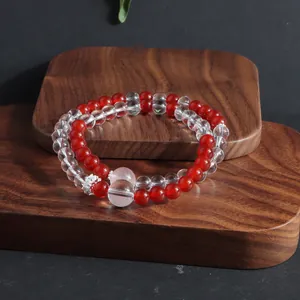 Close-up of a double-layered red and clear crystal bead bracelet on a wooden stand.