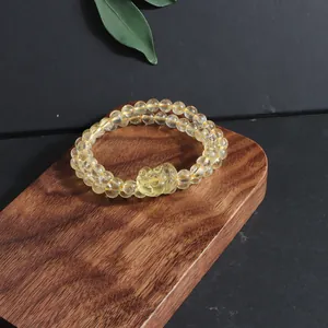 Detailed view of natural yellow citrine bracelet with a carved pixiu charm on wood