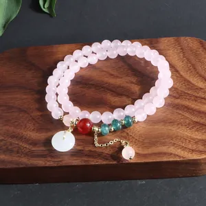 Detalle de primer plano de pulsera multicapa de cuarzo rosa con cuentas de jade real