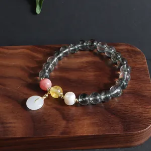 Detail eines Armbands im chinesischen Stil mit grünen Kristallperlen und Jade-Anhänger