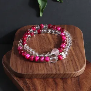 Detail view of handcrafted rose red tiger eye and clear crystal beaded bracelet on wood stand