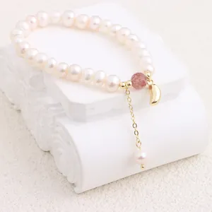 Detail view of a natural freshwater pearl bracelet with a golden crescent charm