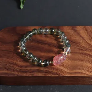 Green phantom crystal bead bracelet with pink lion charm on a wooden display block