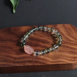 Detailed macro view of Green Phantom Quartz beads and pink carved lion charm bracelet