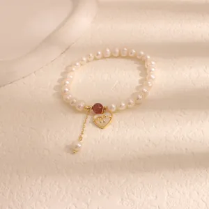 Detail of freshwater pearl bracelet with heart shell charm and strawberry crystal