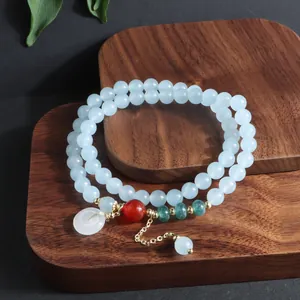 Detalle de pulsera multicapa de piedra azul con hebilla Ping'an y cadena de oro.