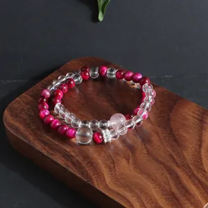 Detail shot of magenta tiger eye and clear crystal double-strand beaded bracelet on wood