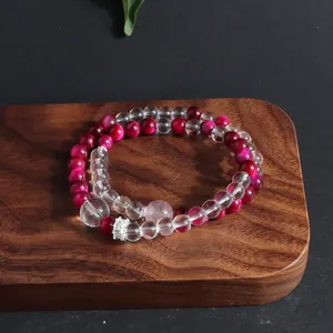 Close-up of magenta tiger eye and clear crystal beaded bracelet on a wooden stand