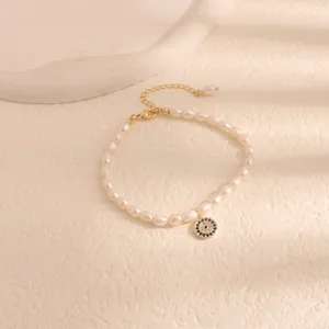 Detailed macro view of white freshwater pearl bracelet featuring a blue evil eye pendant