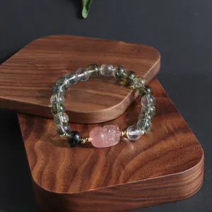Detailed macro view of a green ghost phantom crystal bracelet with a pink lion charm
