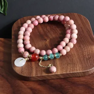 Primer plano de pulsera de cuentas de piedra natural rosa con colgante de jade blanco