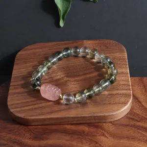 Macro detail of green phantom crystal bracelet with pink carved lion mascot on wood