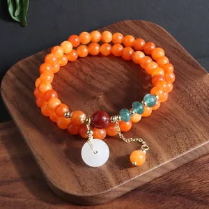 Detalle de las cuentas de piedra natural naranja y el elegante colgante de jade blanco Ping An Kou