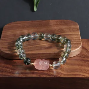 Close-up of green phantom quartz bracelet with a pink hand-carved lion bead