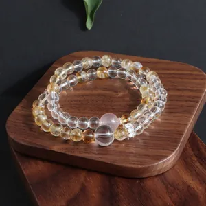 Double-layered natural stone bracelet with clear and yellow beads on a wooden stand.