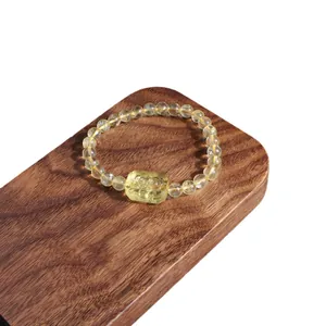 Natural citrine bead bracelet featuring a carved yellow crystal charm on wooden display