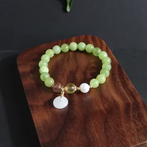 Detailansicht eines chinesischen Armbandes mit grünen Perlen, Weißjade-Anhänger und Perle.