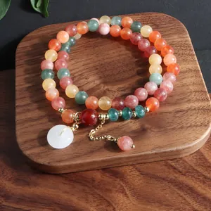 Detalle de pulsera multicapa de piedra natural con colgante de hebilla de la paz.
