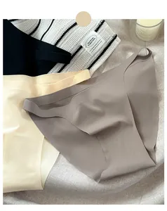 Macrodetail van drie naadloze ijssis-strings in neutrale kleuren op een zachte stof.