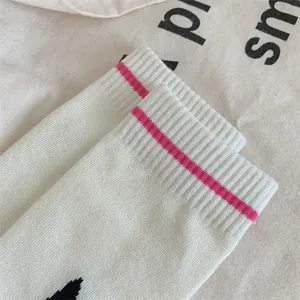 Gros plan détaillé de poignets de chaussettes en coton côtelé blanc avec une rayure rose