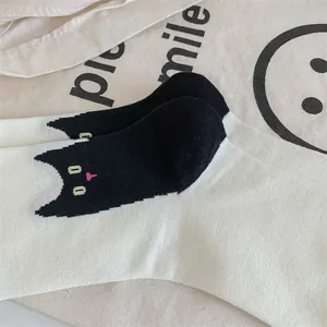 Gros plan sur le motif de chat noir mignon des chaussettes en coton tricoté crème