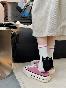 Vue détaillée de chaussettes mi-mollet blanches avec motif de chat noir et rayures roses.