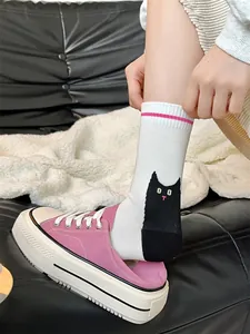 Vue détaillée d'une chaussette blanche mi-mollet avec un joli chat noir sur la jambe
