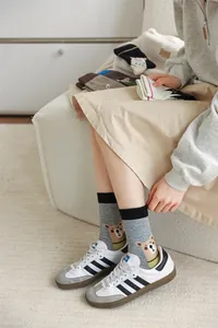 Gros plan de chaussettes mi-mollet grises pour femmes avec un ours mignon